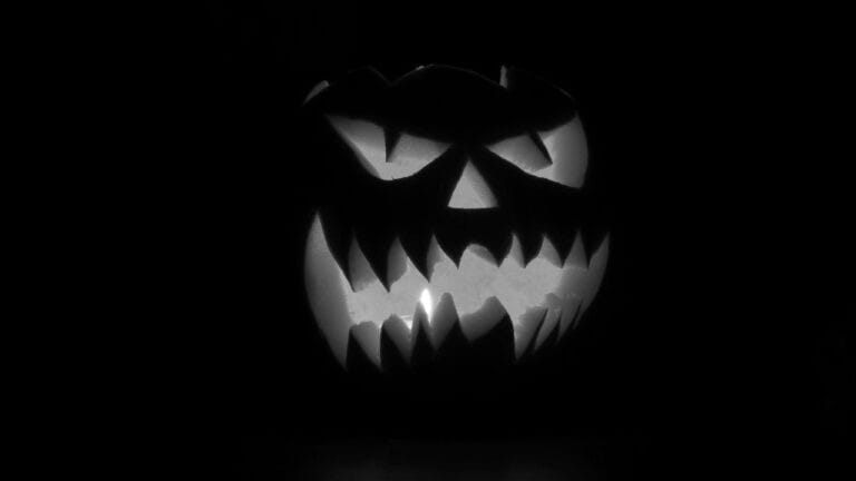 Halloween-Kürbis mit gruseliger Fratze, dunkle Atmosphäre, für Themen rund um Feste und Veranstaltun.