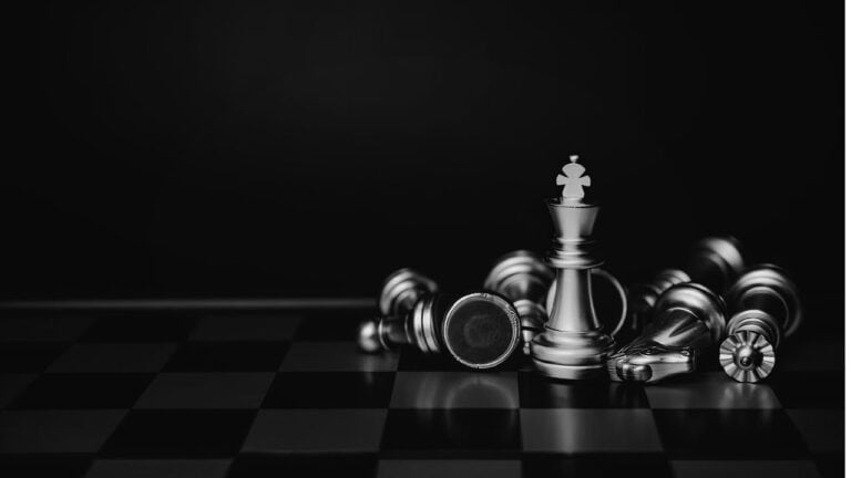 Schachfiguren, darunter eine weiße Königin, auf einem dunklen Schachbrett.