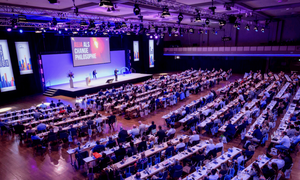 Große Konferenz mit Ilja Grzeskowitz als Redner auf Bühne.